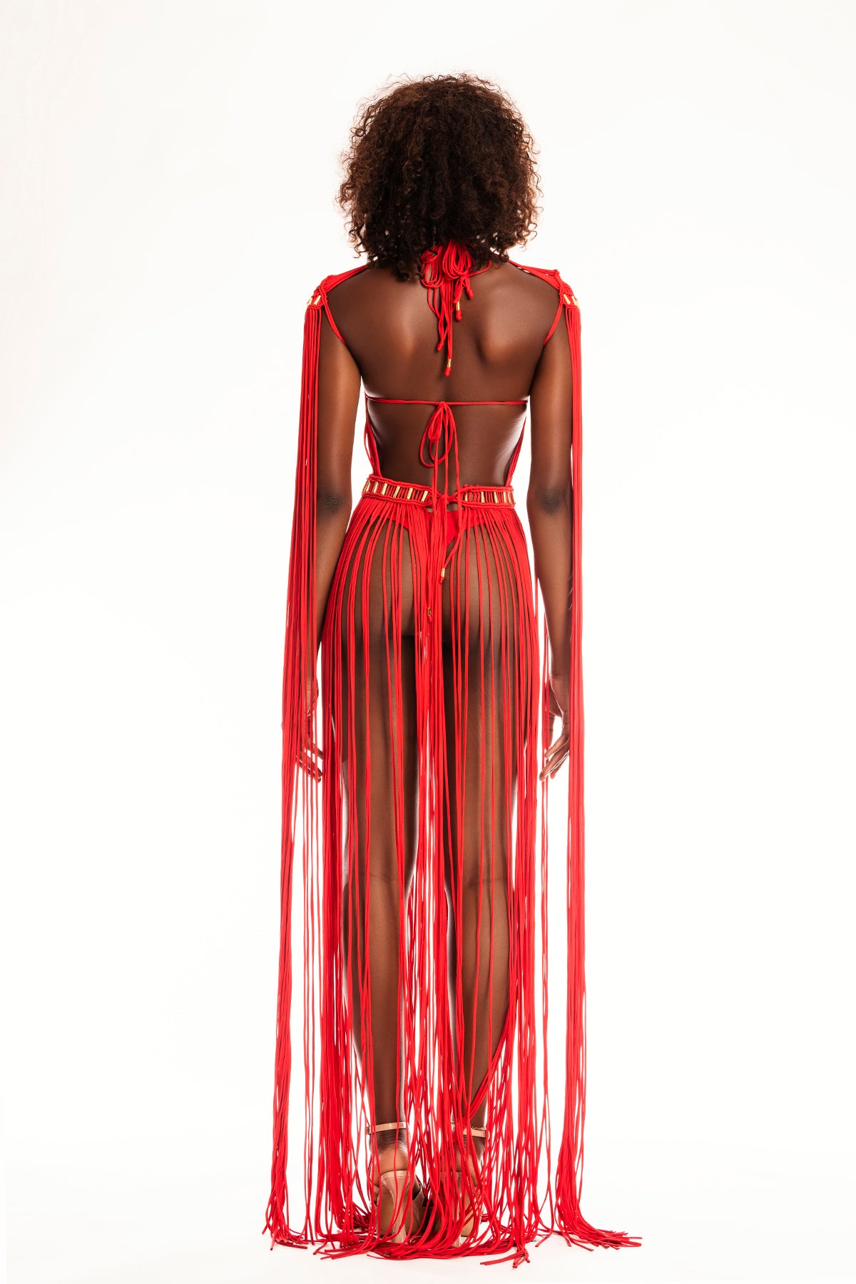 Back view of the Renacer dress, featuring an open-back macramé structure with intricate weaves and gold embellishments.